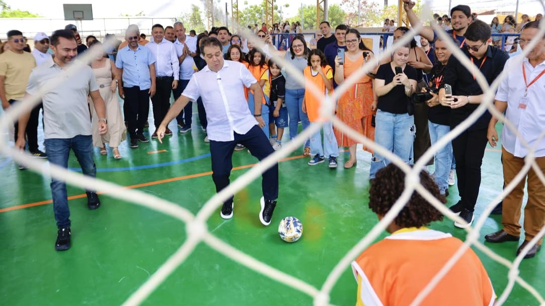 prefeito evandro chutando uma bola numa quadra de escola